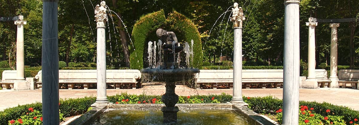 Una fuente entre columnas y setos en un jardín de Aranjuez.