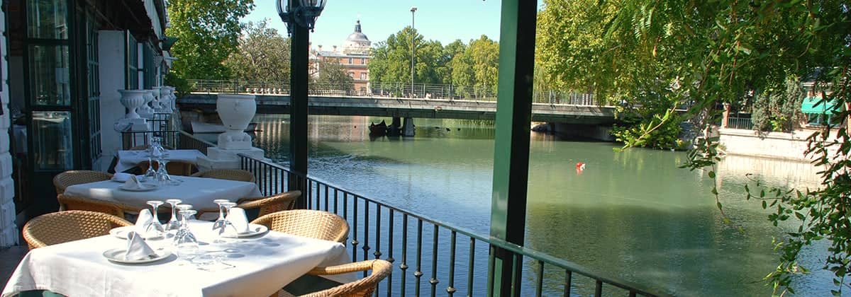 La terraza del restaurante sobre el río, con el puente y la cúpula del palacio al fondo.